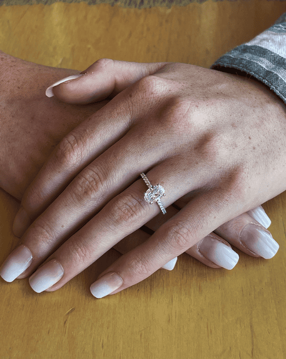Two hands show care and love, with a Winter Jewelry halo diamond ring highlighting a special commitment.