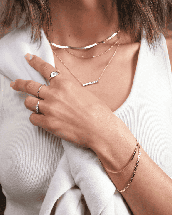 A woman shows off Winter Jewelry, making her outfit look stylish with bright, shiny gold rings and bracelets.