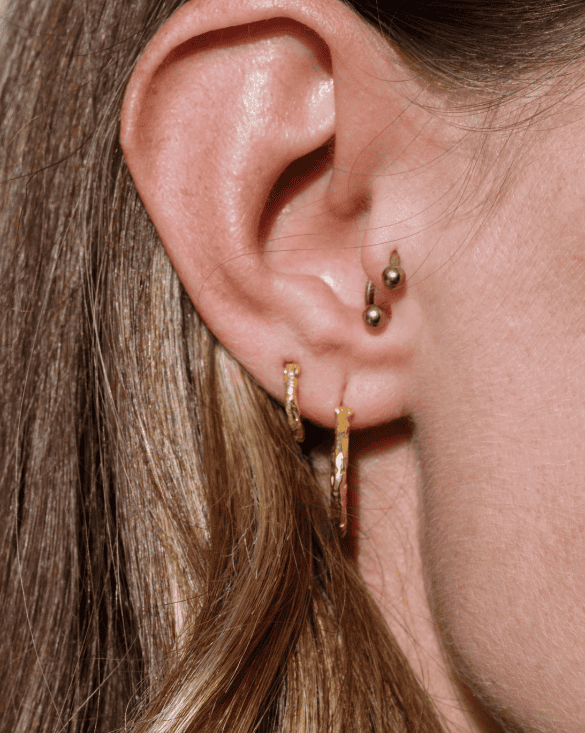 A person shows off four Winter Jewelry gold earrings, highlighting stylish ear choices from Williamsville, New York.