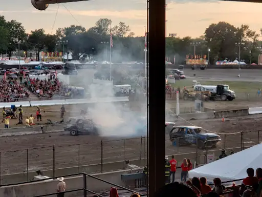 People watch a thrilling car derby, some wearing Winter Jewelry, while staff and responders stand ready for safety.