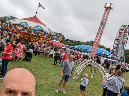 People enjoy a fun fair wearing Winter Jewelry, sharing happy moments together outdoors on a cloudy day.